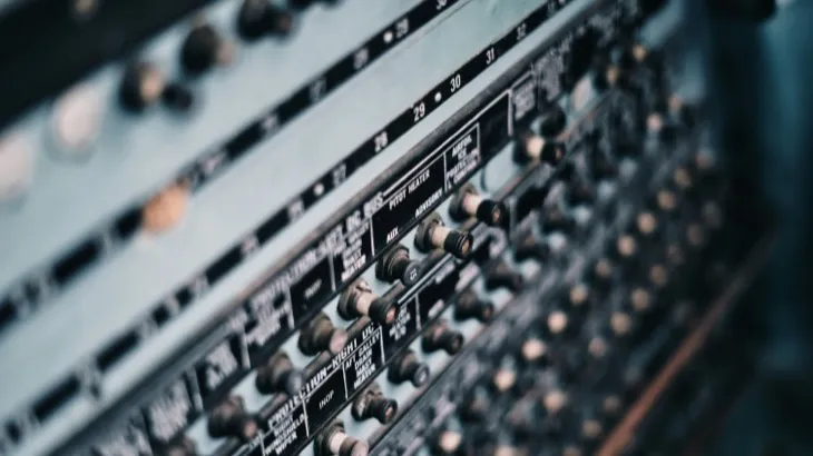 Close-up of an audio mixing board covered in knobs and switches, representing algorithm choice and user control over social media feeds