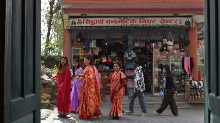 People walking past a colorful local shop with goods displayed in the window, representing foot traffic to small independent stores