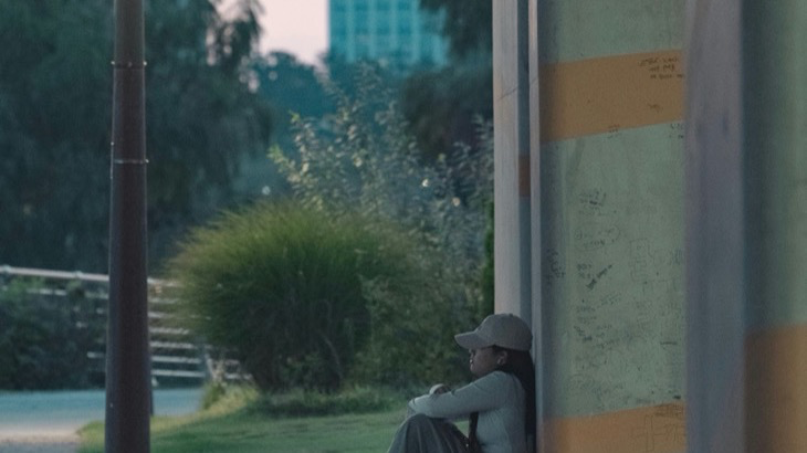 Person sitting alone at dusk in an urban setting, representing the loneliness and social isolation of the friendship recession