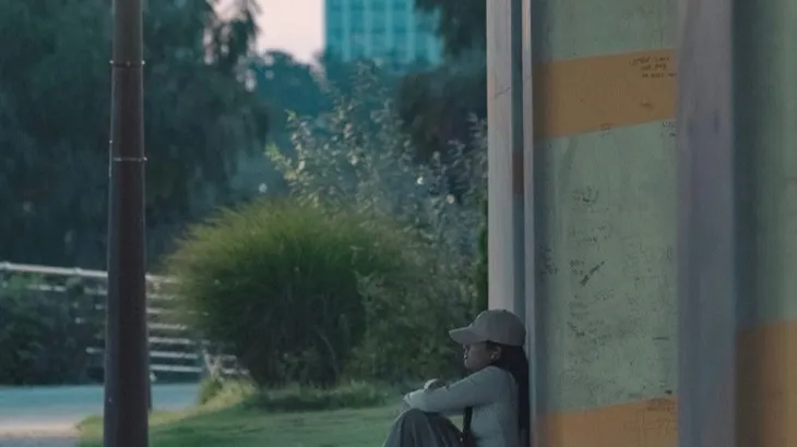 Person sitting alone at dusk in an urban setting, representing the loneliness and social isolation of the friendship recession