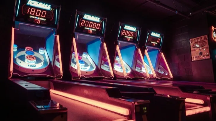 A row of lit arcade machines with score displays, illustrating the gamification of habits