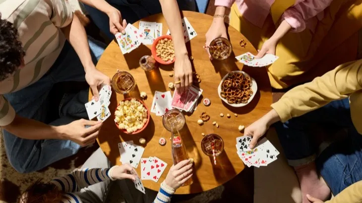 Friends gathered around a table playing cards with snacks, showing the social side of gamified routines