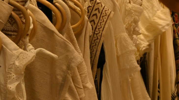 Hand browsing through clothing rack representing Gen Z conscious consumer habits and the shift toward mindful spending