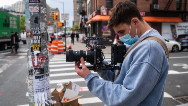 Young content creator with camera filming in a city street