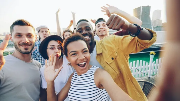 Diverse group of friends taking a selfie outdoors, representing the joy of adult friendships and real-world social connection