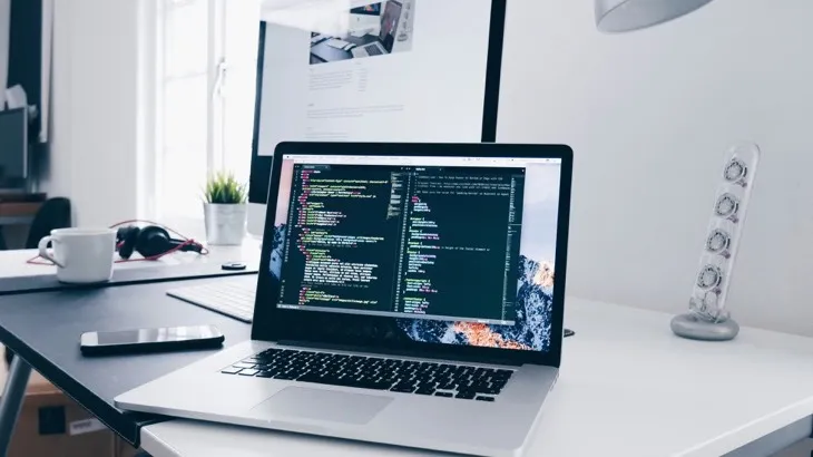 Laptop displaying lines of code on a bright desk, representing developers building on an open public API instead of a closed platform
