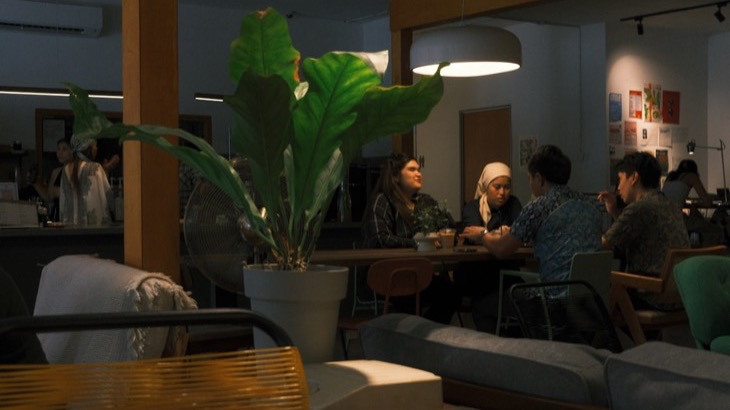 People gathered inside a warmly lit local cafe, building community connections