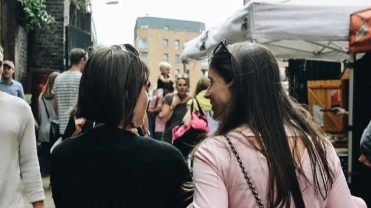 Two friends exploring a local street market on the weekend, representing local discovery and spontaneous weekend plans